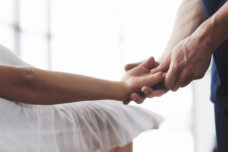 Fisioterapeuta a massajar mão de mulher com rizartrose ou artrose no dedo polegar